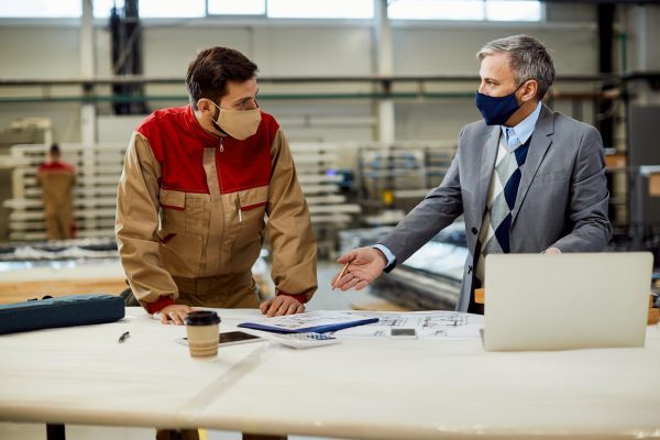 project-manager-talking-carpenter-while-examining-blueprints-workshop_637285-11835